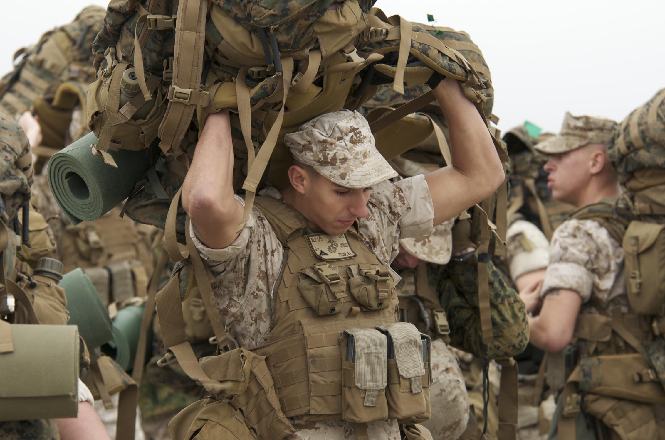 US Navy 091027-N-3592S-044 Lance Cpl. Brandon Focer, an A-gunner with Charlie Company, 2nd Platoon, 24th Marine Expeditionary Unit, heaves his pack over his head as he and other Marines wait to board landing craft utilities.jpg